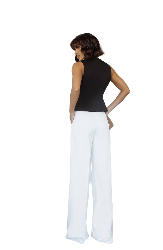 Woman wearing a black sleeveless top and white pants on a white background