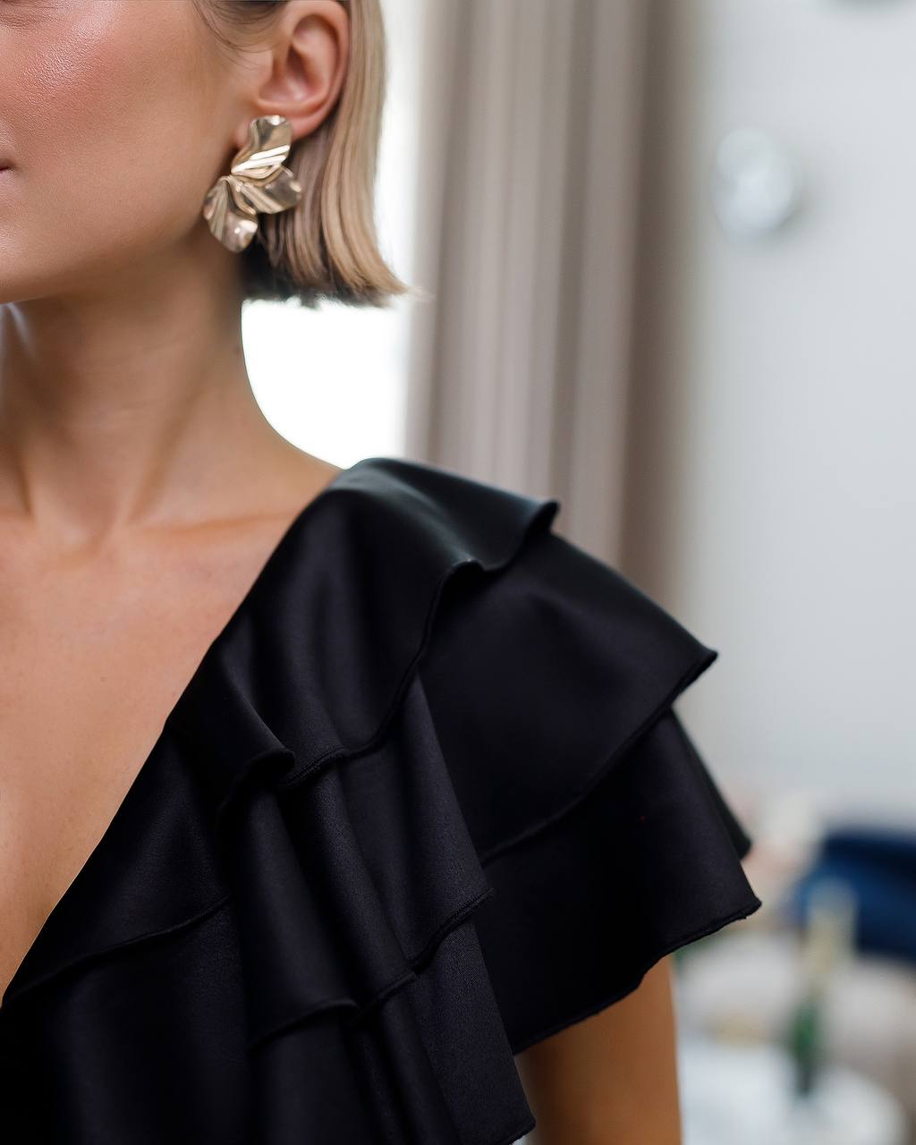 Close-up of a person wearing a black ruffled top with a blurred background