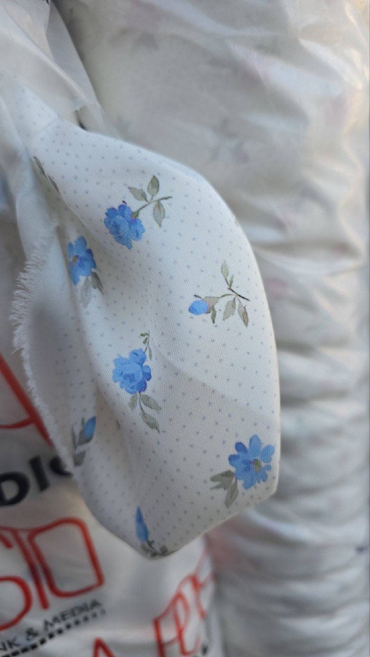 Close-up of a white sleeve with blue floral patterns on a blurred background