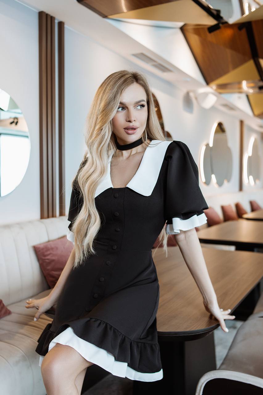 Woman in a black dress with white accents in an elegant interior setting