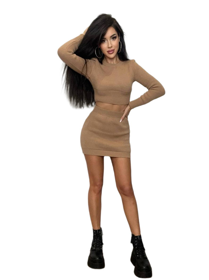 Woman wearing a beige two-piece outfit with black boots on a white background
