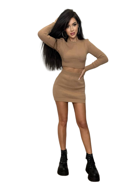 Woman wearing a beige two-piece outfit with black boots on a white background