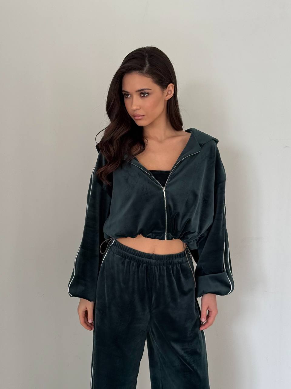 Woman wearing a dark green tracksuit against a plain background
