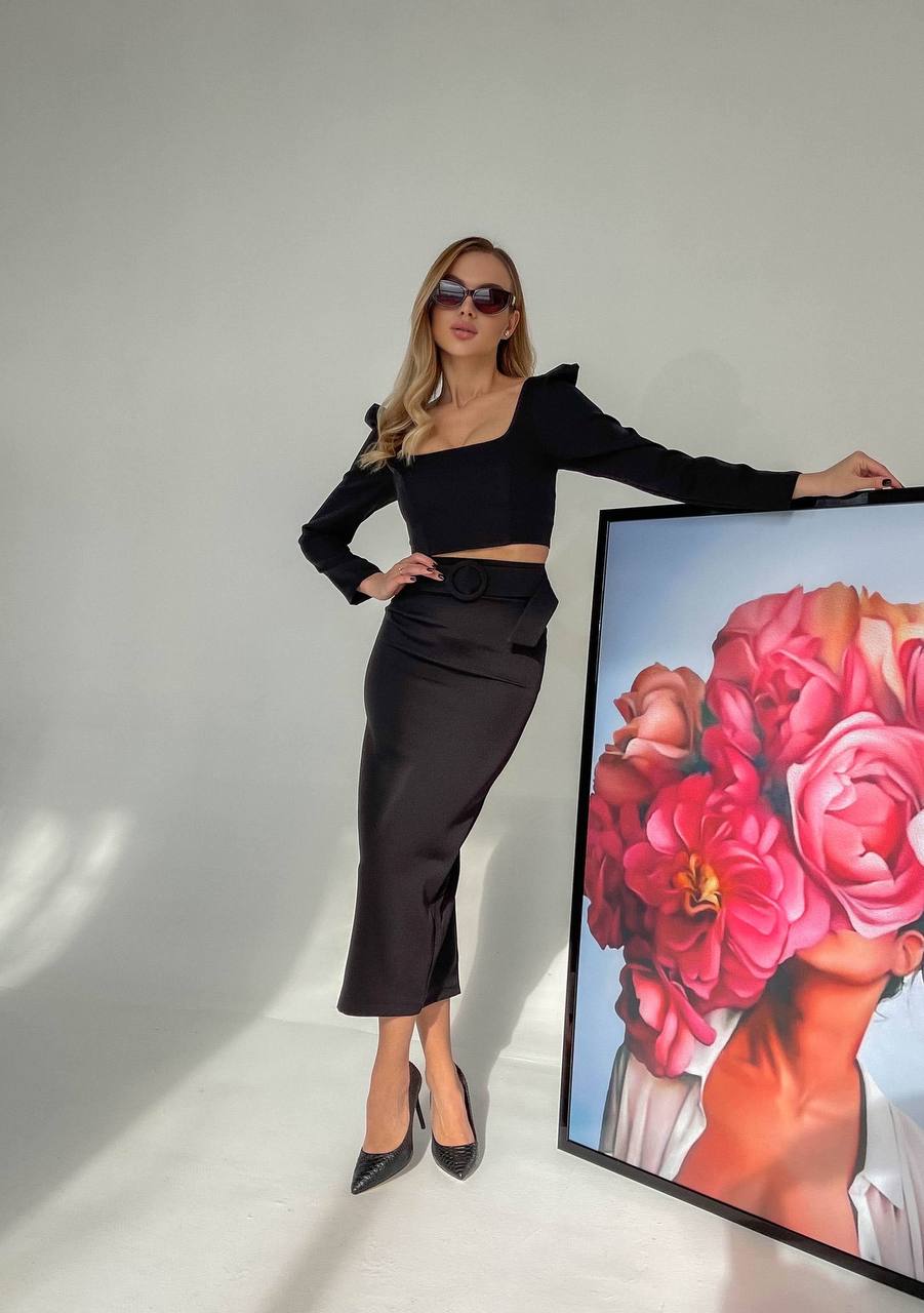 Woman in black outfit posing next to a floral painting