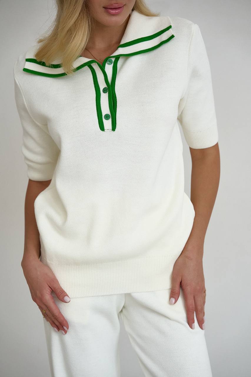 White sweater with green accents worn by a person on a plain background