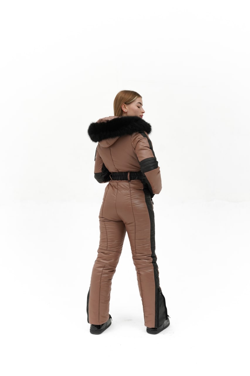 Person wearing a brown and black snowsuit with fur trim on a white background