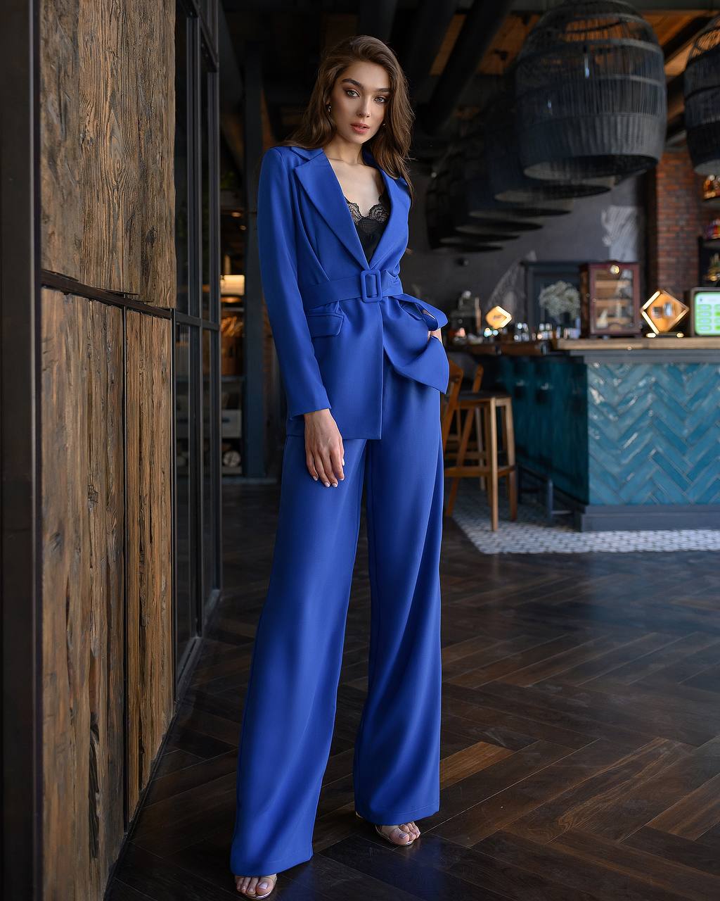 Woman in a blue outfit standing in a stylish interior setting.