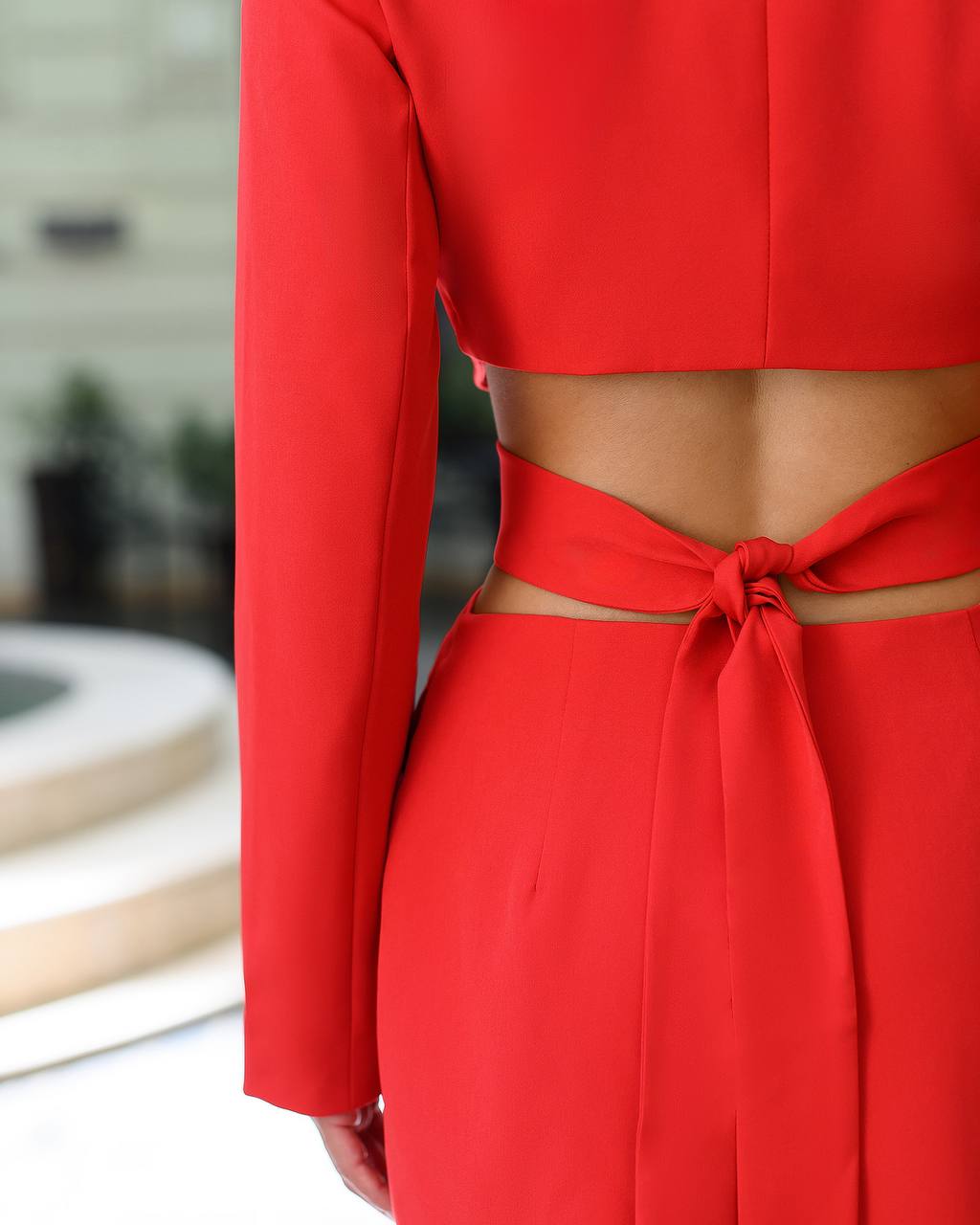 Red outfit with long sleeves and a tied waist, blurred background