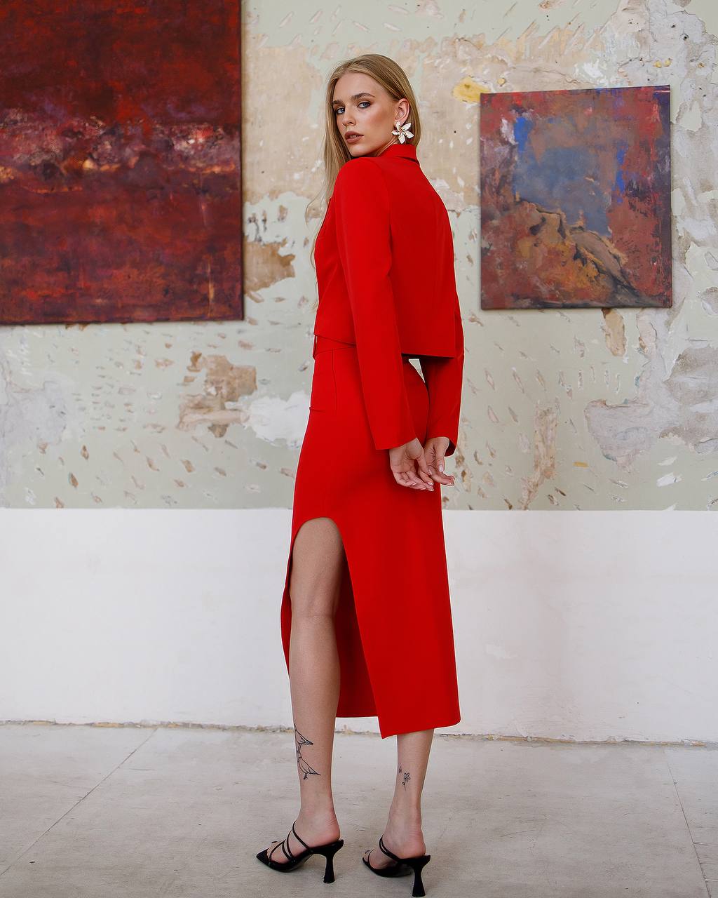 Woman in a red dress standing in an art gallery with abstract paintings on the wall.