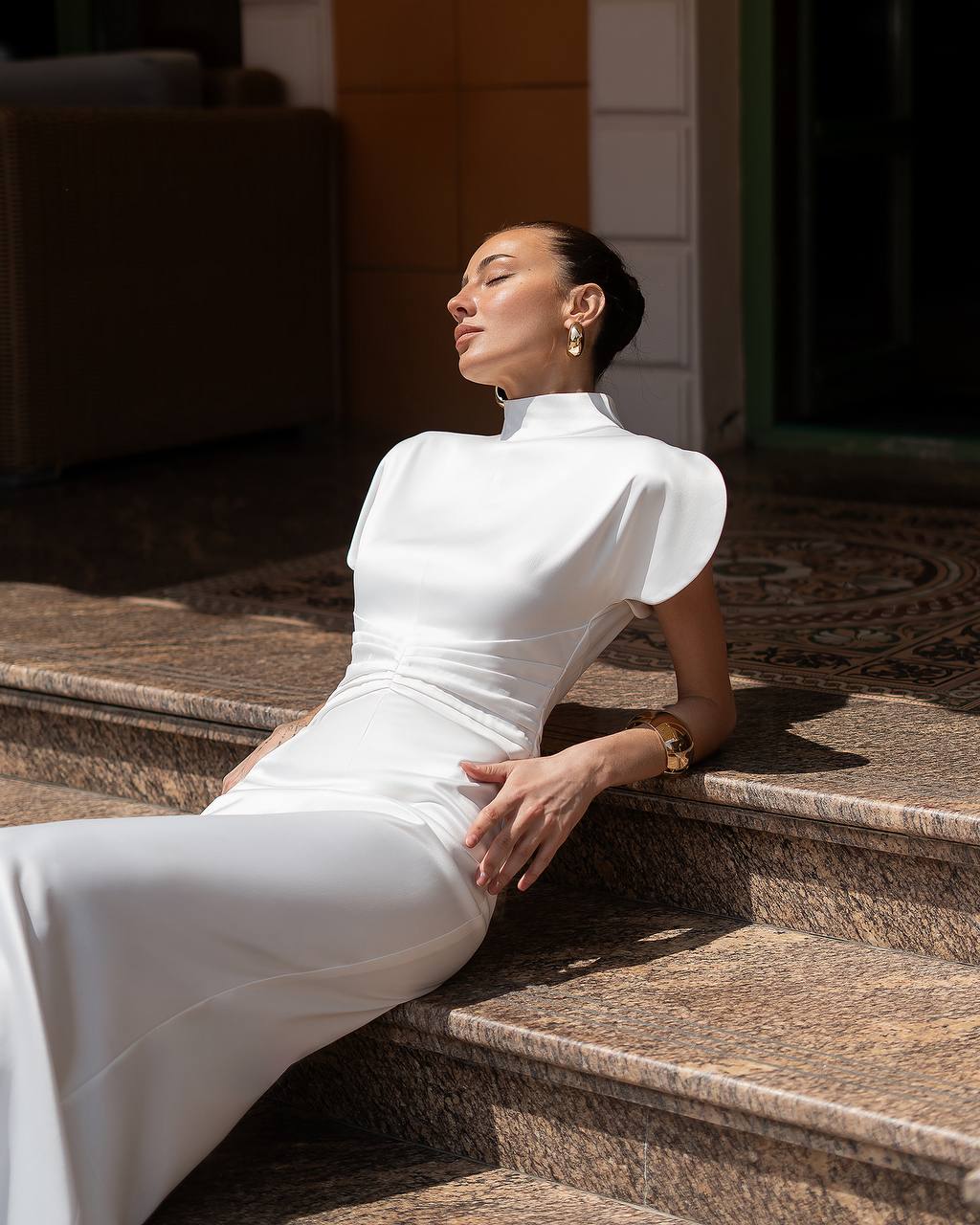 Woman in a white dress sitting on stone steps outdoors