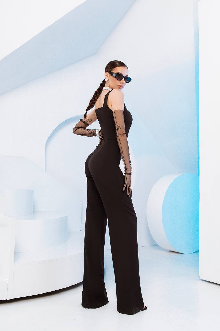 Woman in a black outfit with sheer sleeves against a modern, abstract background