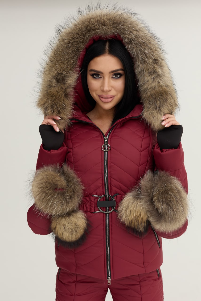 Person wearing a red snowsuit with fur hood and cuffs on a white background