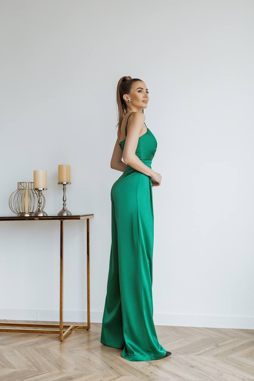 Woman in a green evening gown standing in a room with a table and candles.
