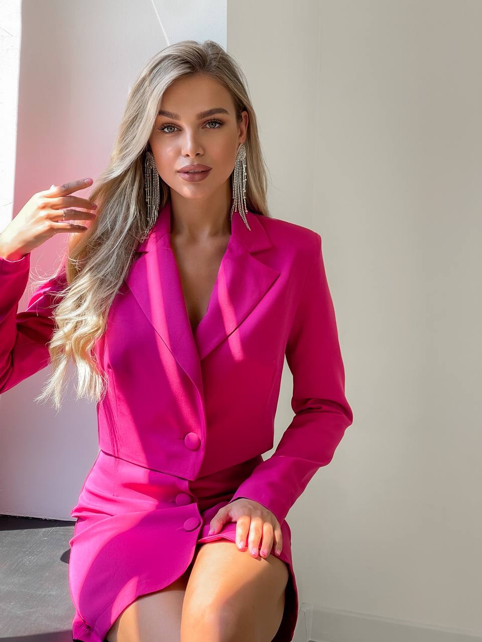 Woman wearing a bright pink blazer dress against a neutral background