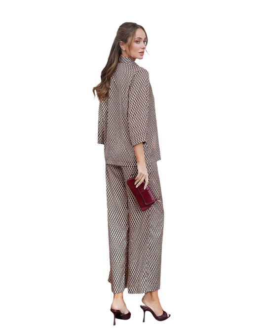 Woman wearing a patterned outfit holding a red clutch on a white background