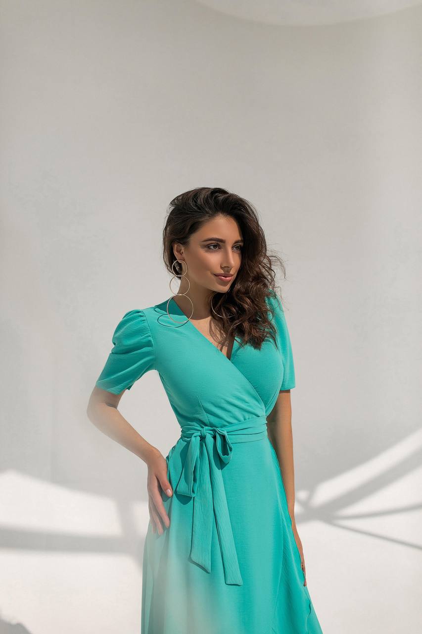 Woman wearing a teal dress against a white background