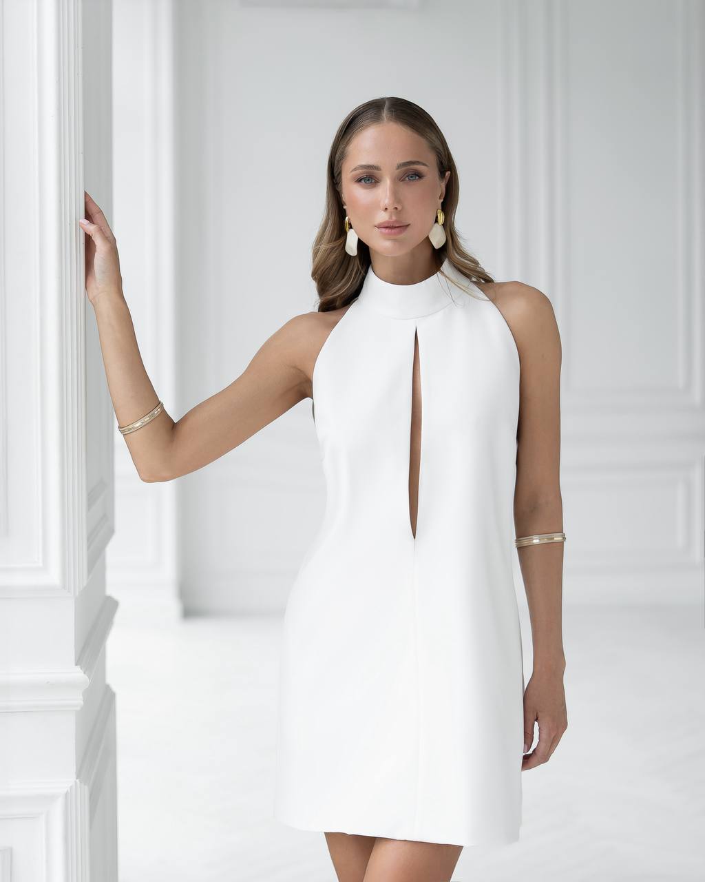 Woman wearing a white halter neck dress against a white background