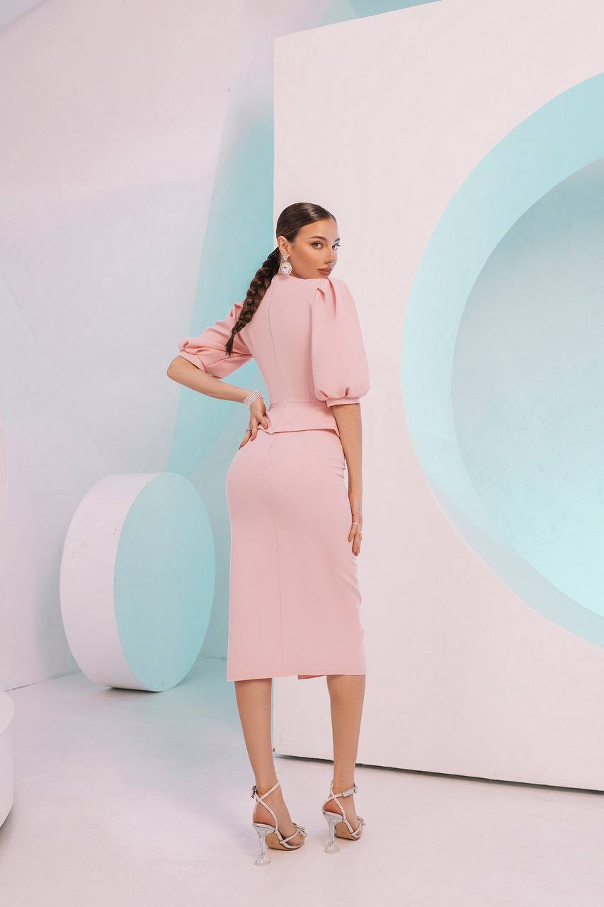 Woman in a pink outfit standing against a modern, minimalistic background