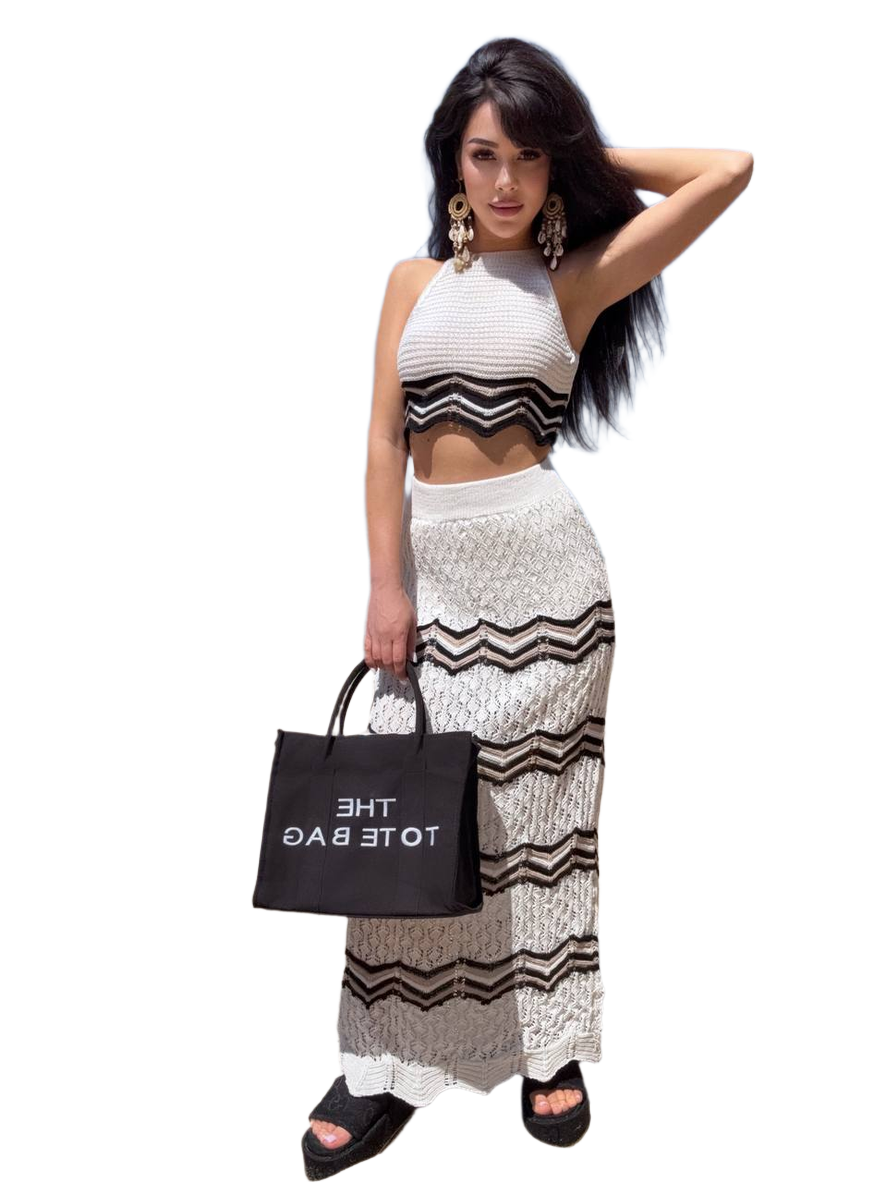 Woman in a black and white outfit holding a black tote bag with 'THE TOTE BAG' text.