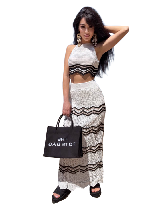 Woman in a black and white outfit holding a black tote bag with 'THE TOTE BAG' text.