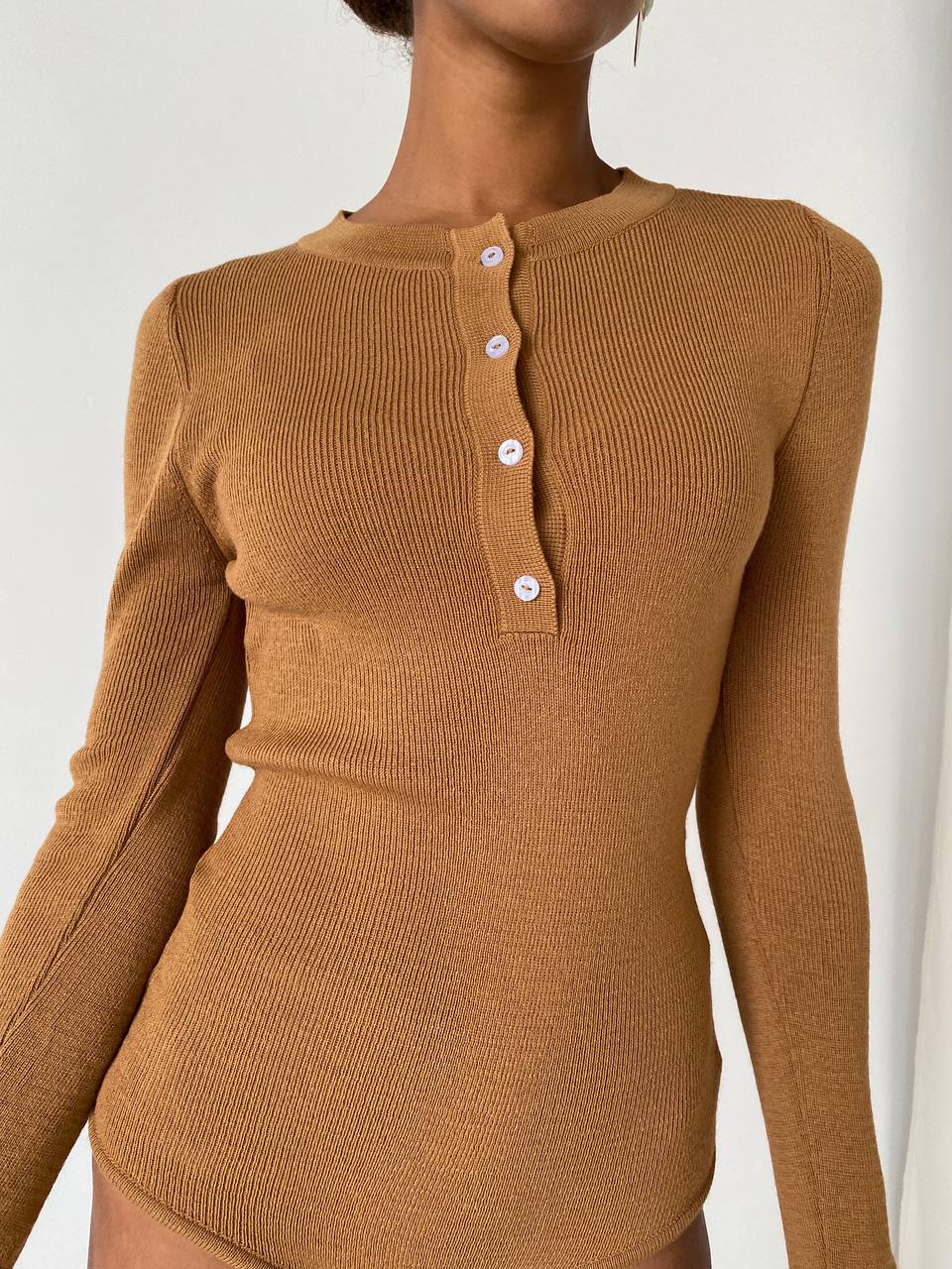 Brown ribbed long-sleeve top worn by a person on a white background
