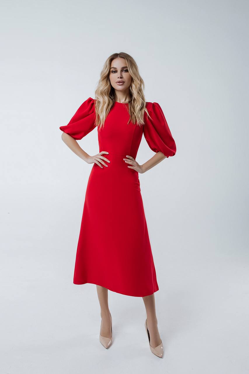 Woman wearing a red dress with puff sleeves on a white background