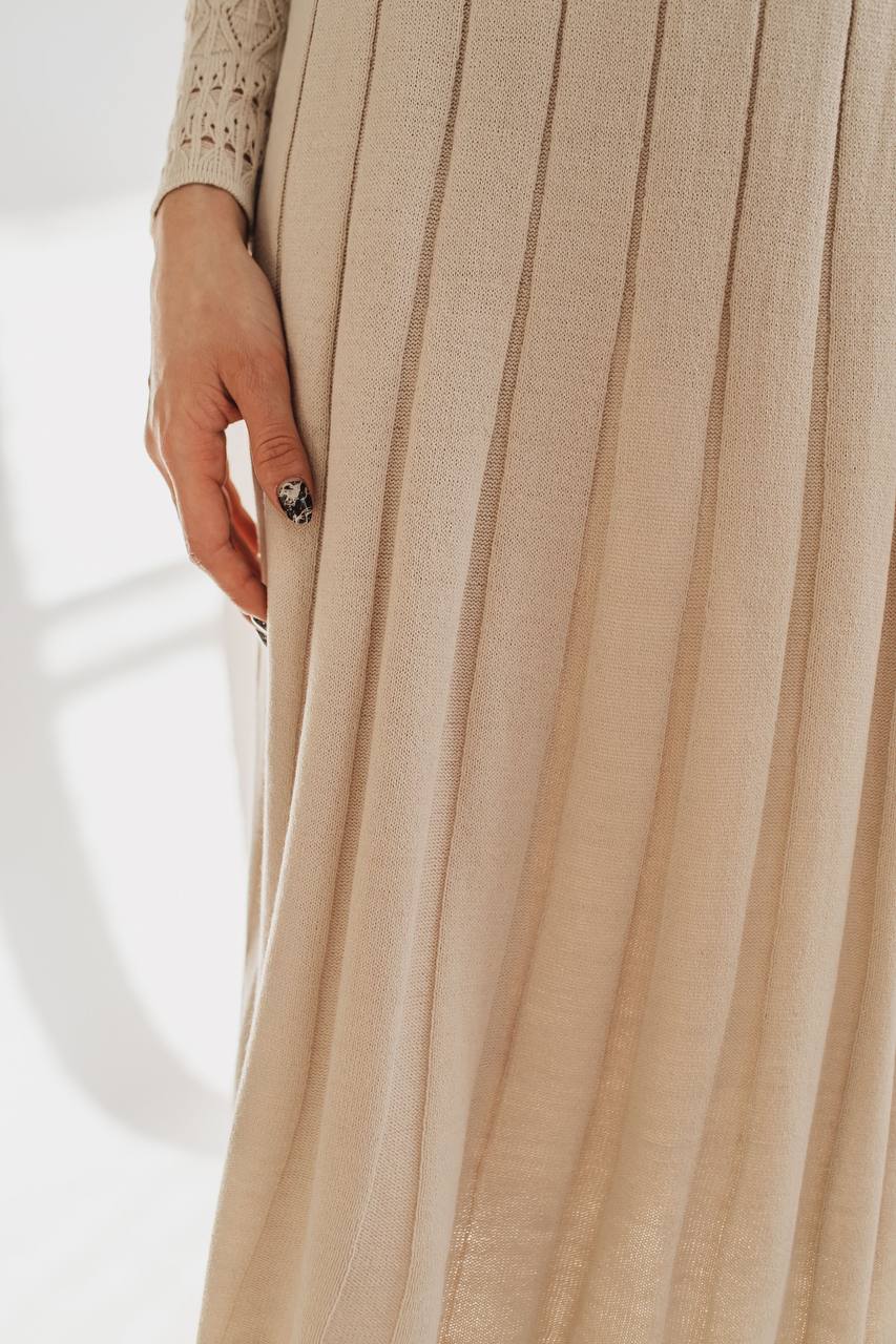 Close-up of a beige pleated skirt with a white background