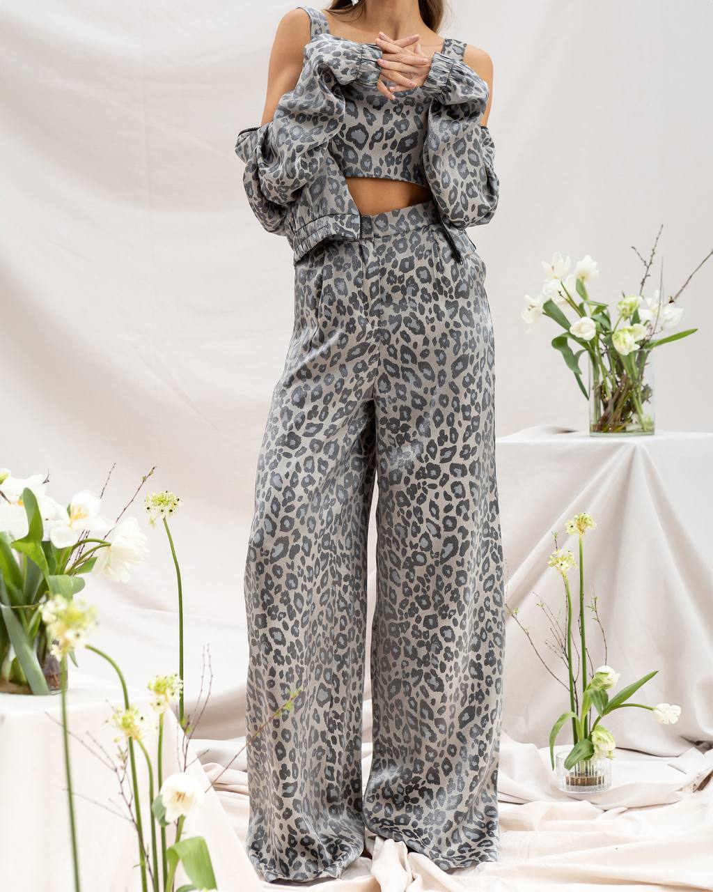 Person wearing a leopard print outfit with a white background and flowers.