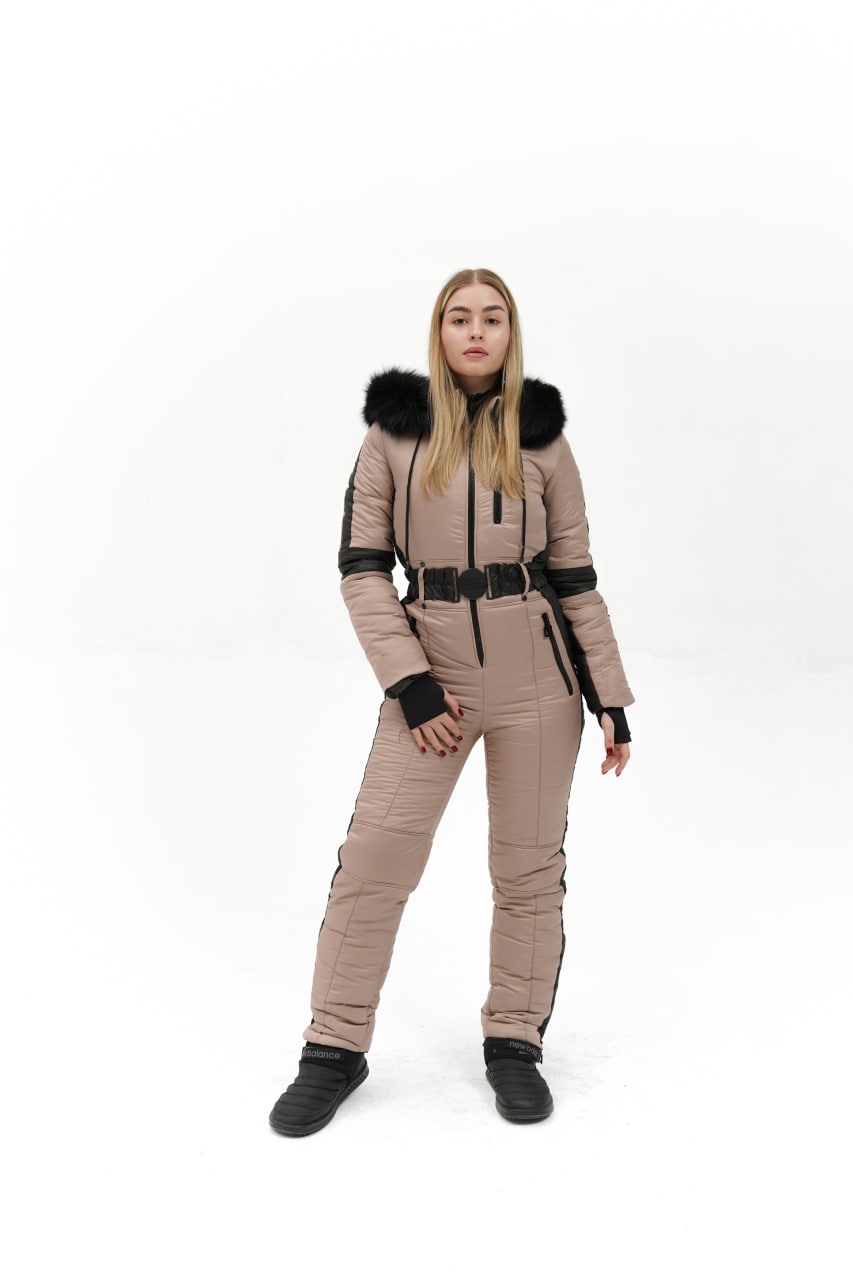 Woman wearing a beige snowsuit with black accents on a white background