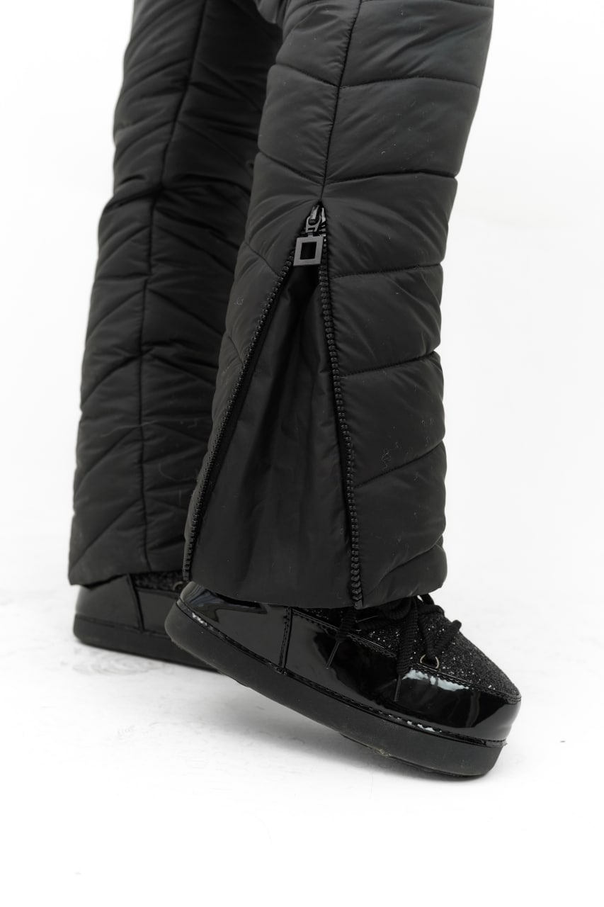 Black puffer pants with attached black shoes on a white background