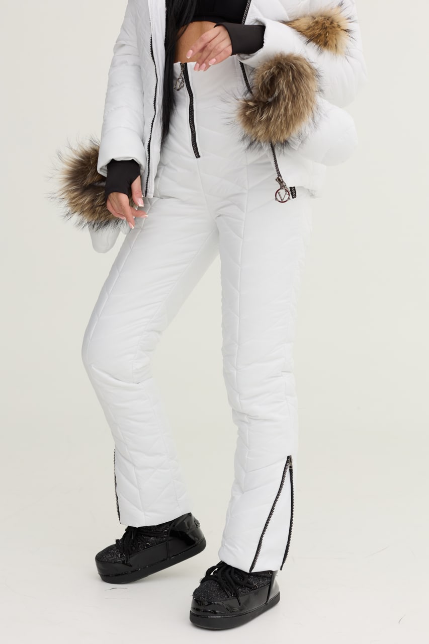 Person wearing white snow pants with fur-lined hood on a light gray background