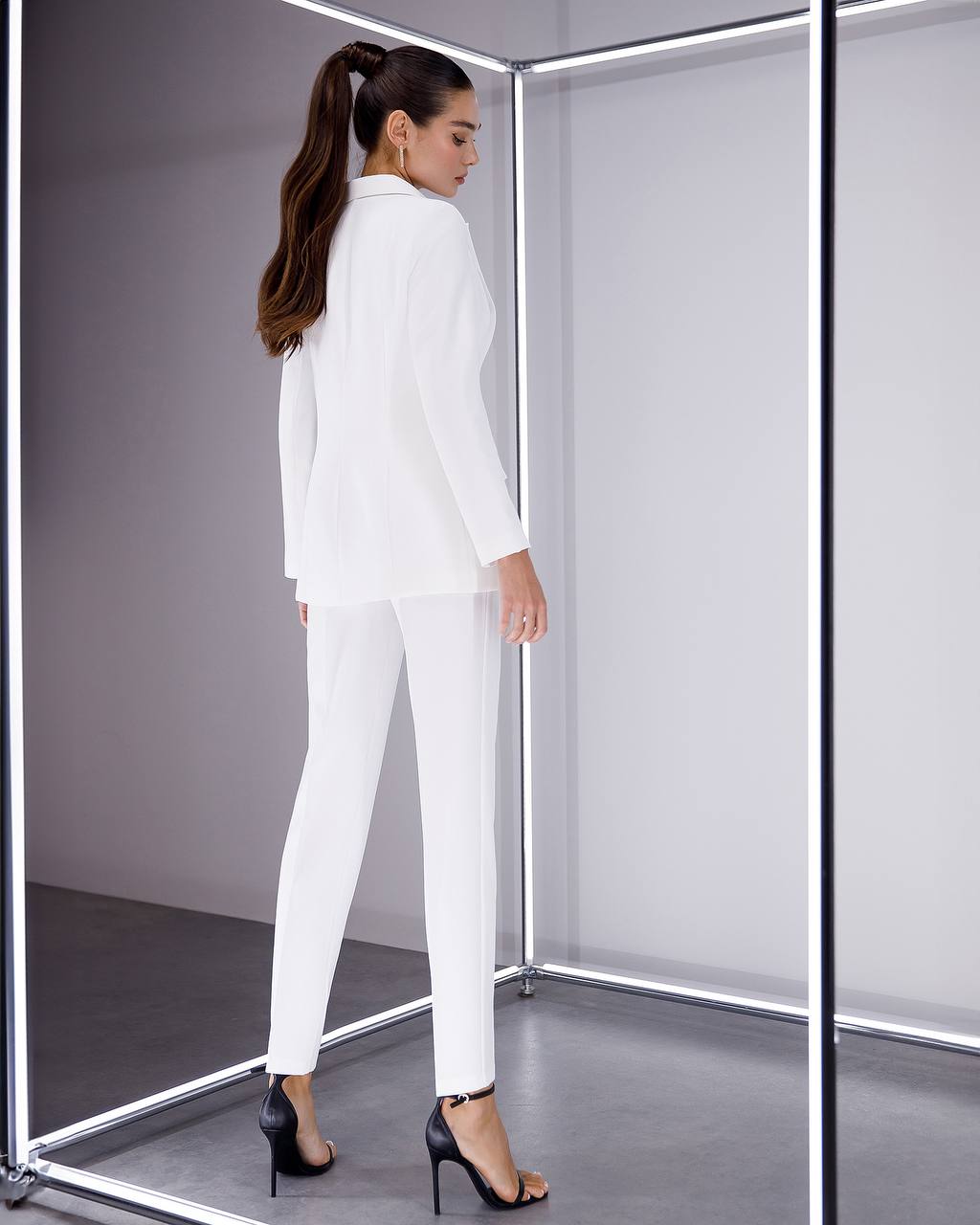 Woman trying on a white suit in a fitting room.
