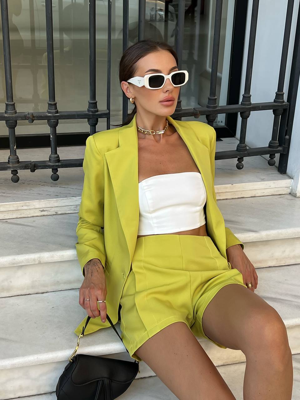 Woman in a bright yellow outfit sitting on steps outdoors
