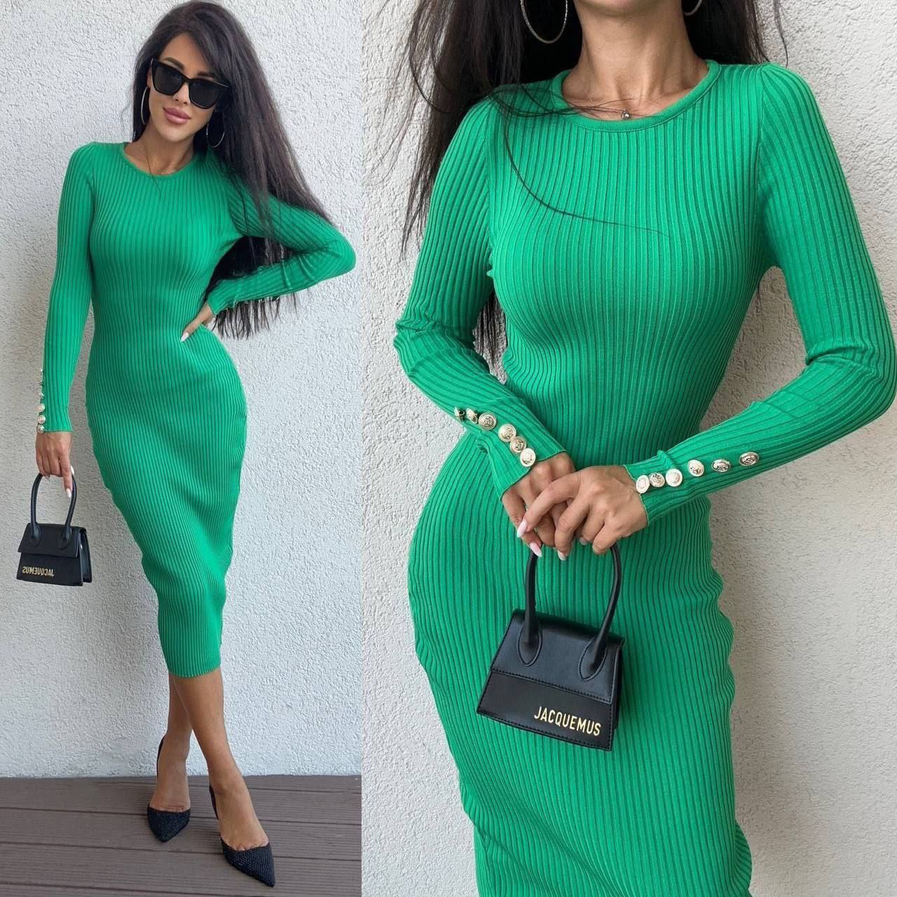 Green ribbed dress with long sleeves and button details, worn by a model holding a black handbag.