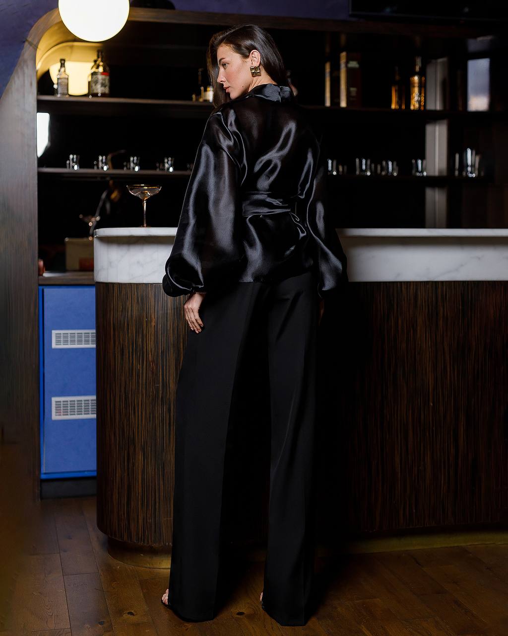 Woman in a black outfit standing in a bar setting
