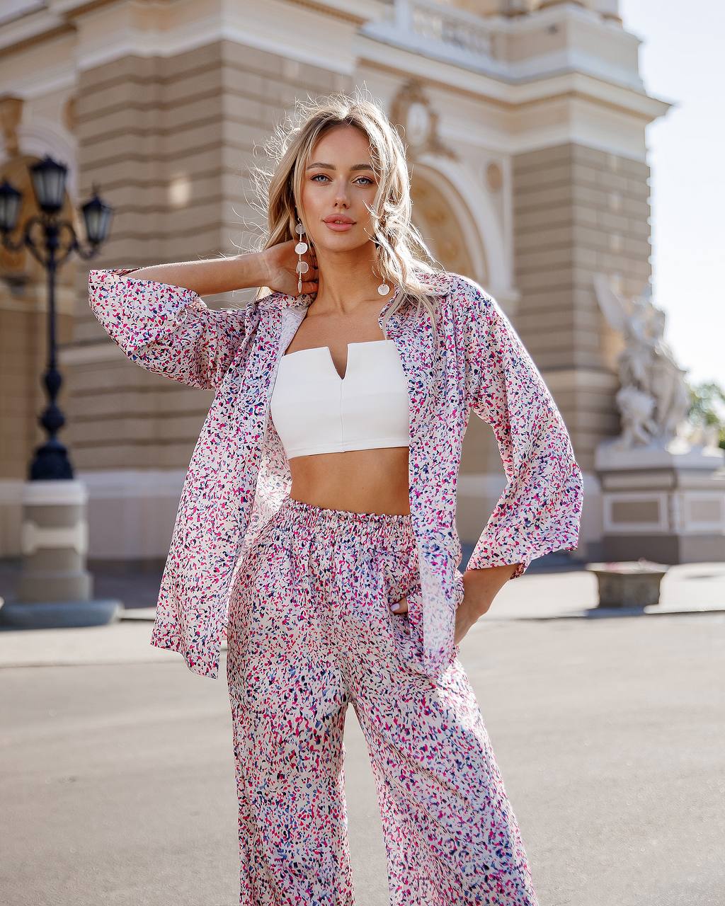 Woman in a floral outfit standing in front of an architectural building
