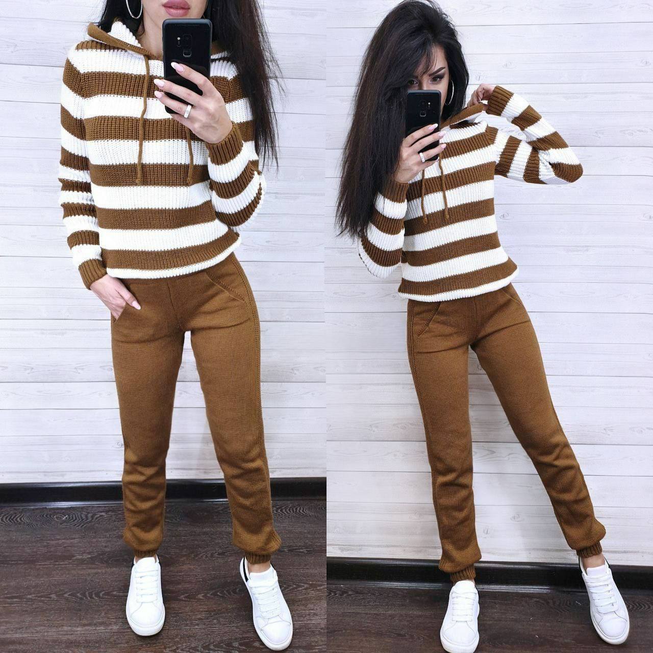 Person wearing a brown and white striped sweater and brown pants, taking a mirror selfie.