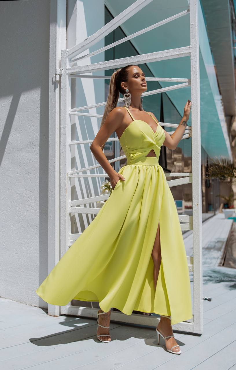 Woman in a bright yellow dress standing in front of a modern architectural structure.