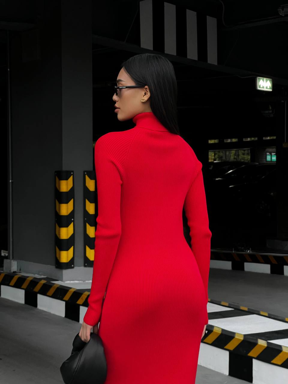 Woman in a red dress standing in a dark industrial setting