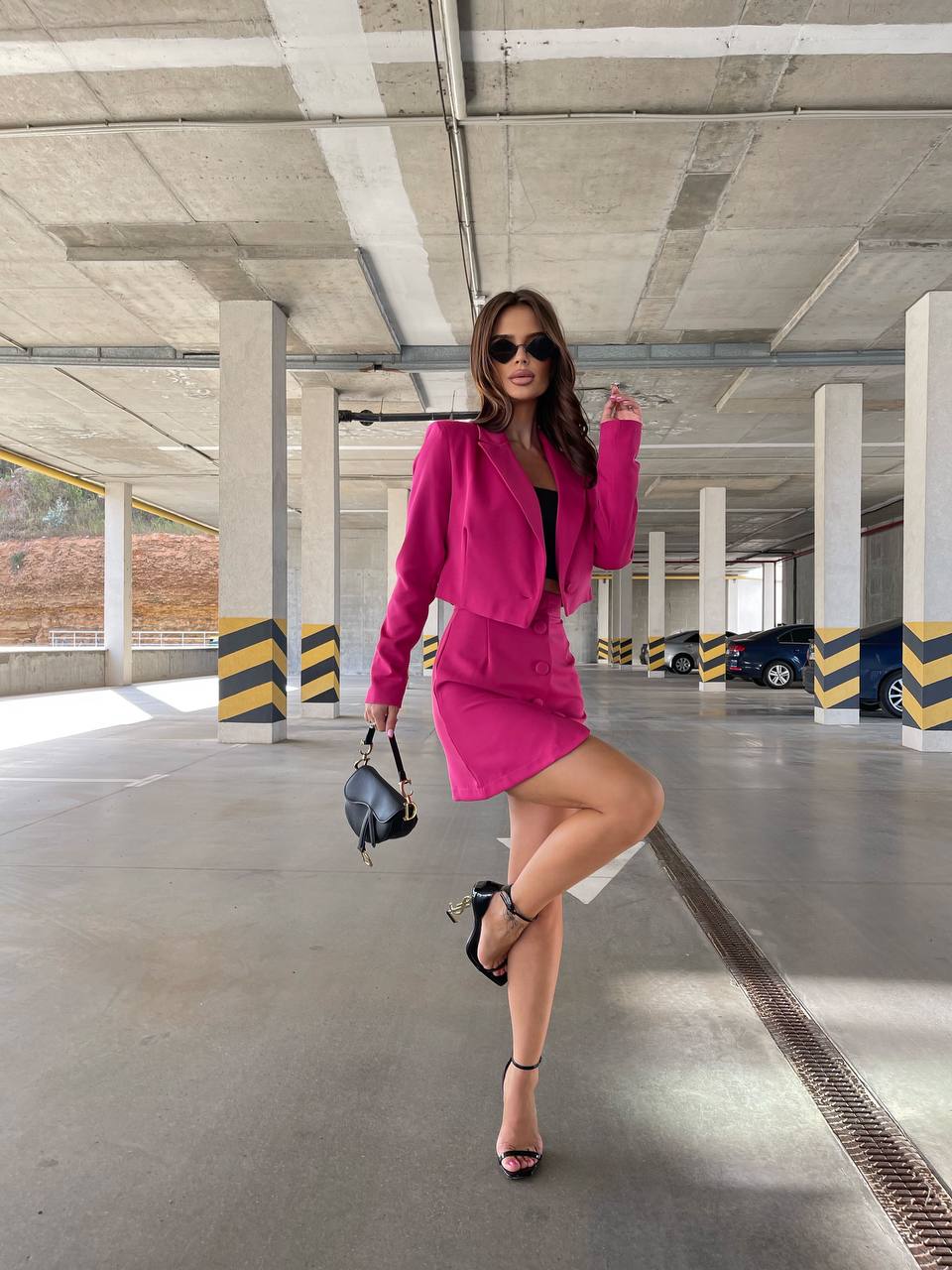 Woman in a pink outfit posing in an underground parking lot