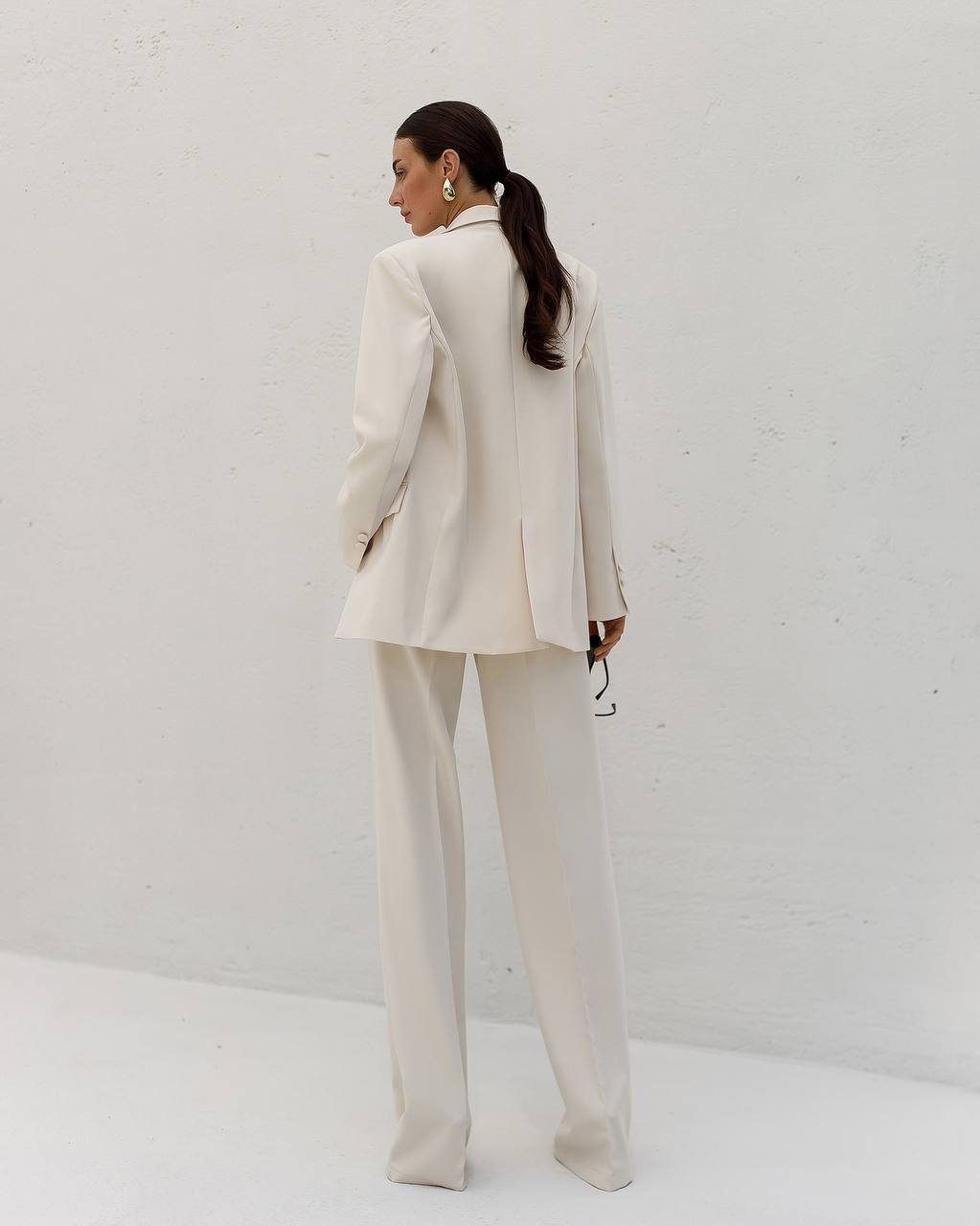 Person wearing a beige suit standing against a white background