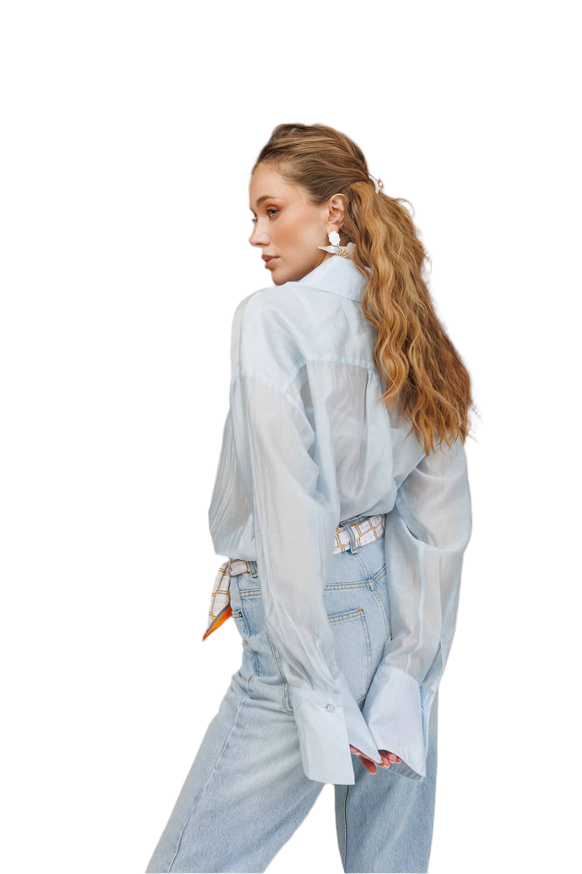 Woman wearing a light blue oversized shirt and jeans on a white background