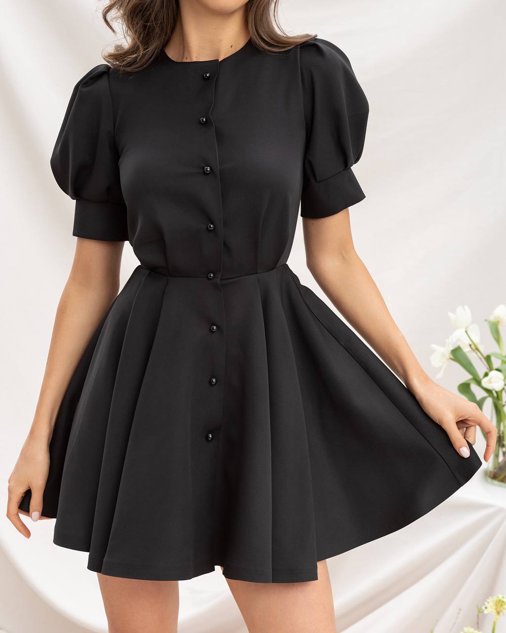 Black dress with puff sleeves worn by a person on a white background