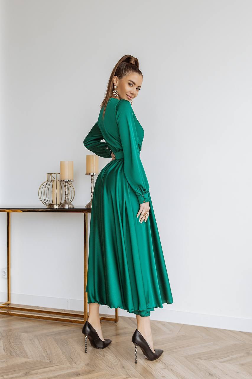 Woman in a green dress standing in a room with a table and candles.
