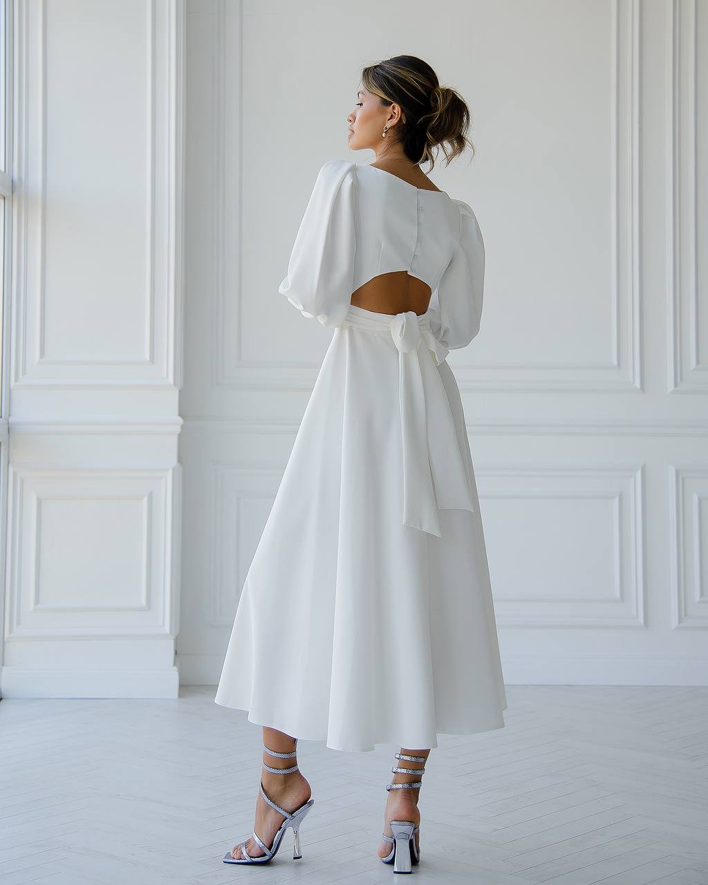 Woman wearing a white dress with a cut-out back in a minimalistic setting