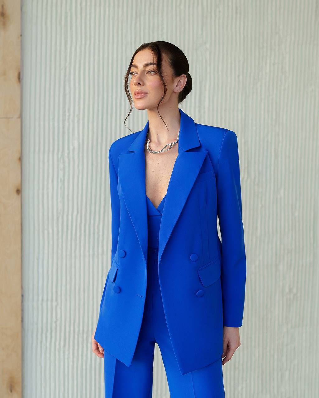 Woman wearing a blue suit against a textured wall.
