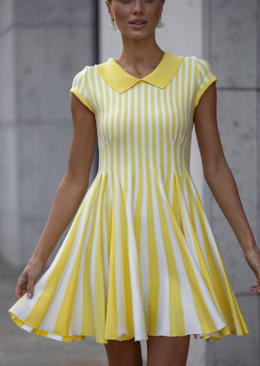 Woman wearing a yellow and white striped dress against a neutral background