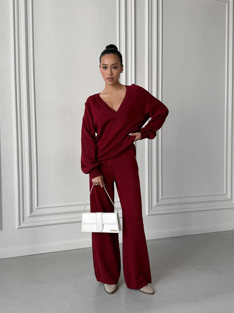 Woman wearing a burgundy outfit with a white wall background
