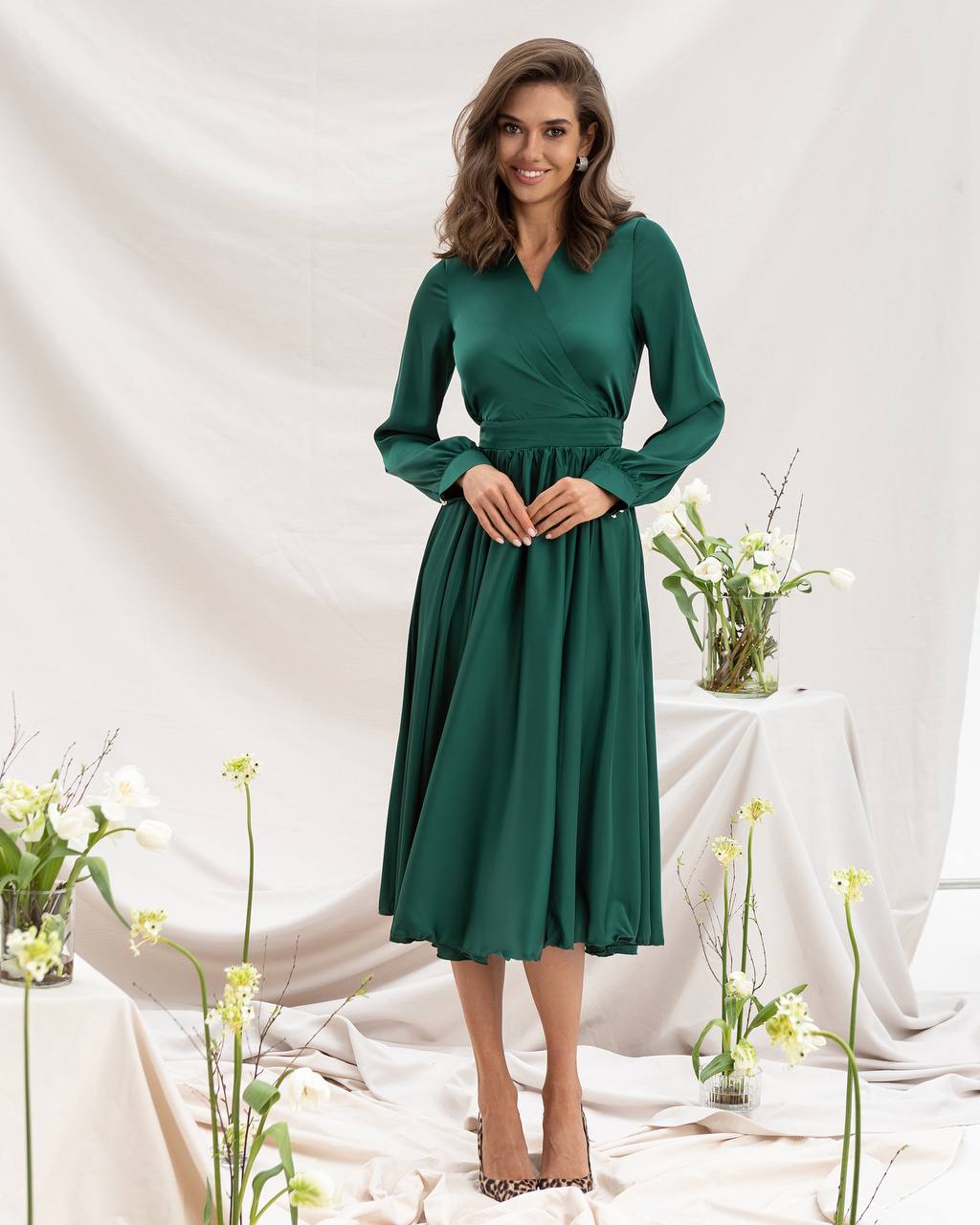 Woman wearing a green dress standing in a decorated room with flowers.