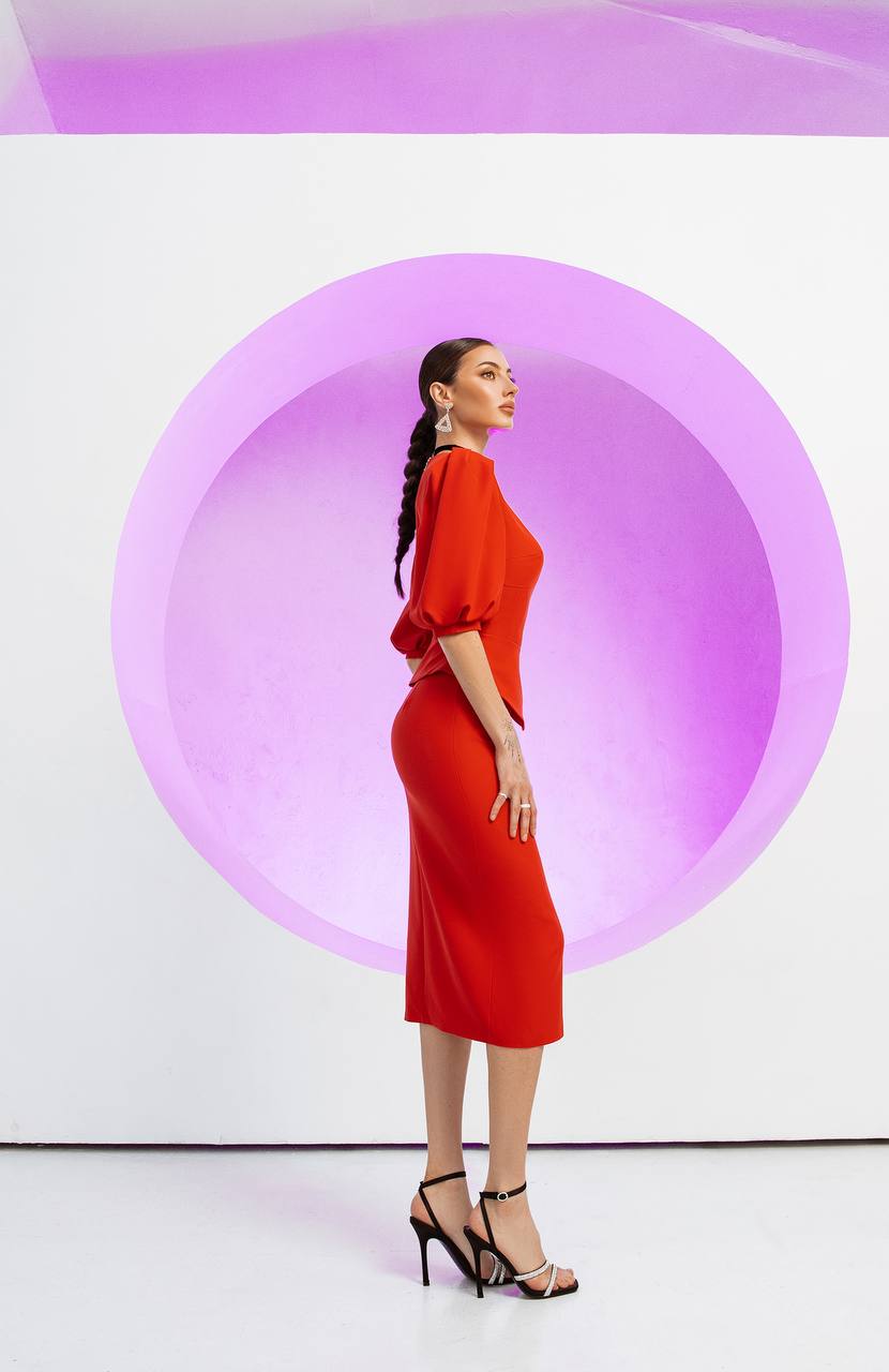 Woman in a red dress standing against a white background with a large pink circle.